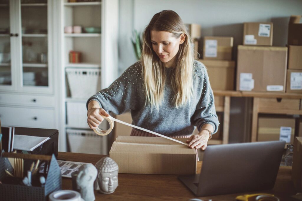 Woman smiling while taping a moving box