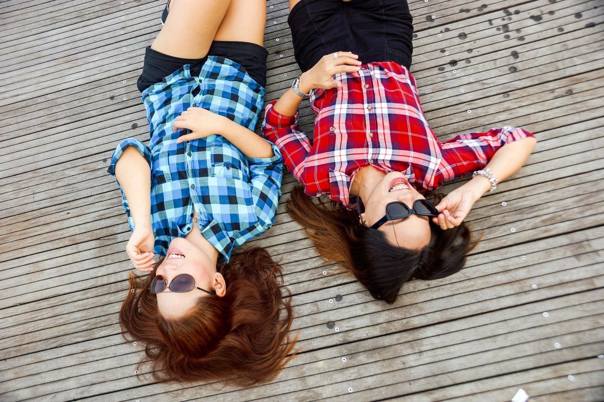 Two young women laying on their backs on a wooden floor